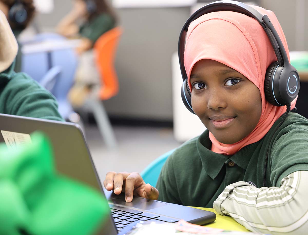 Elementary student smiling and posing together in a classroom.